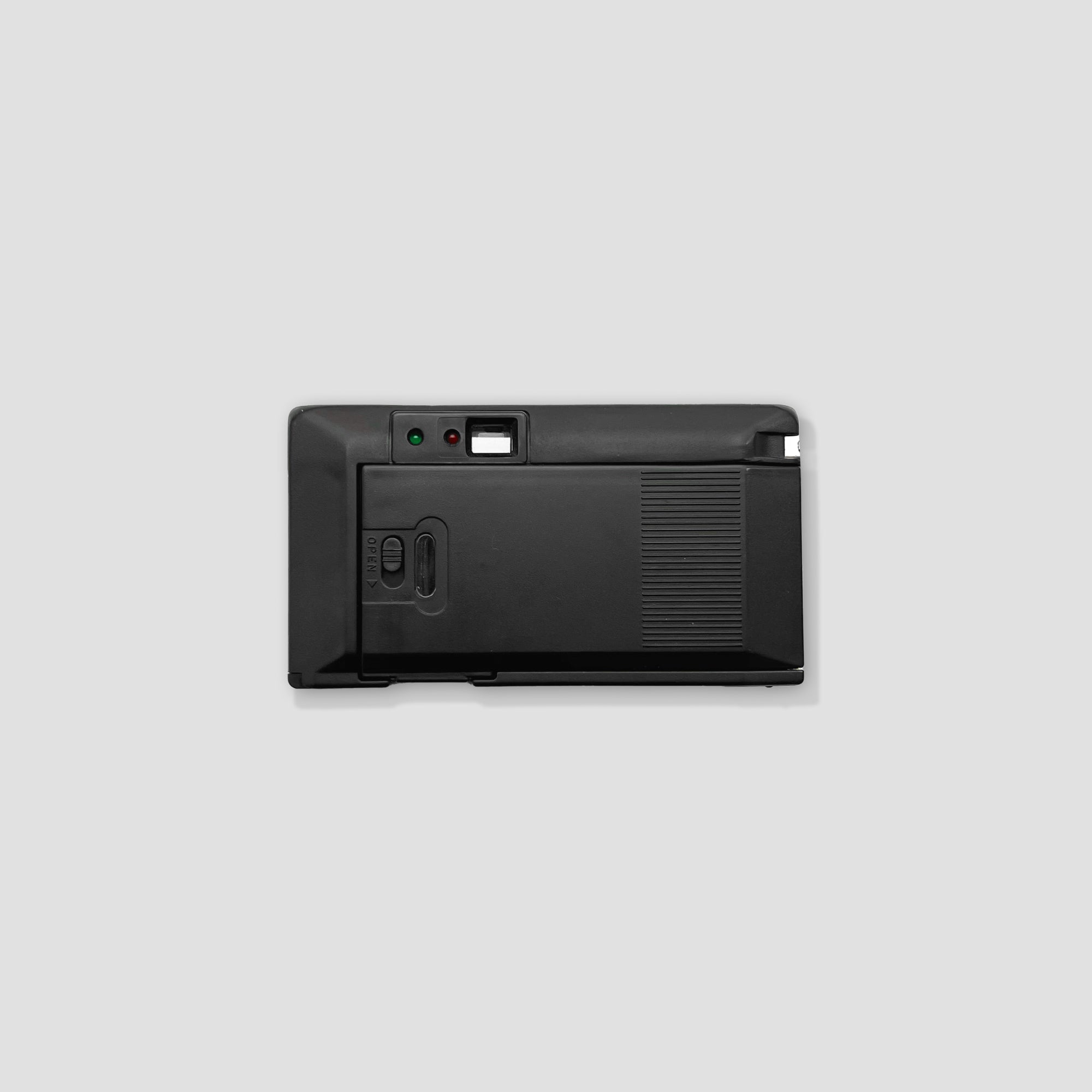 Compact camera displayed on a table with accessories for film photography.