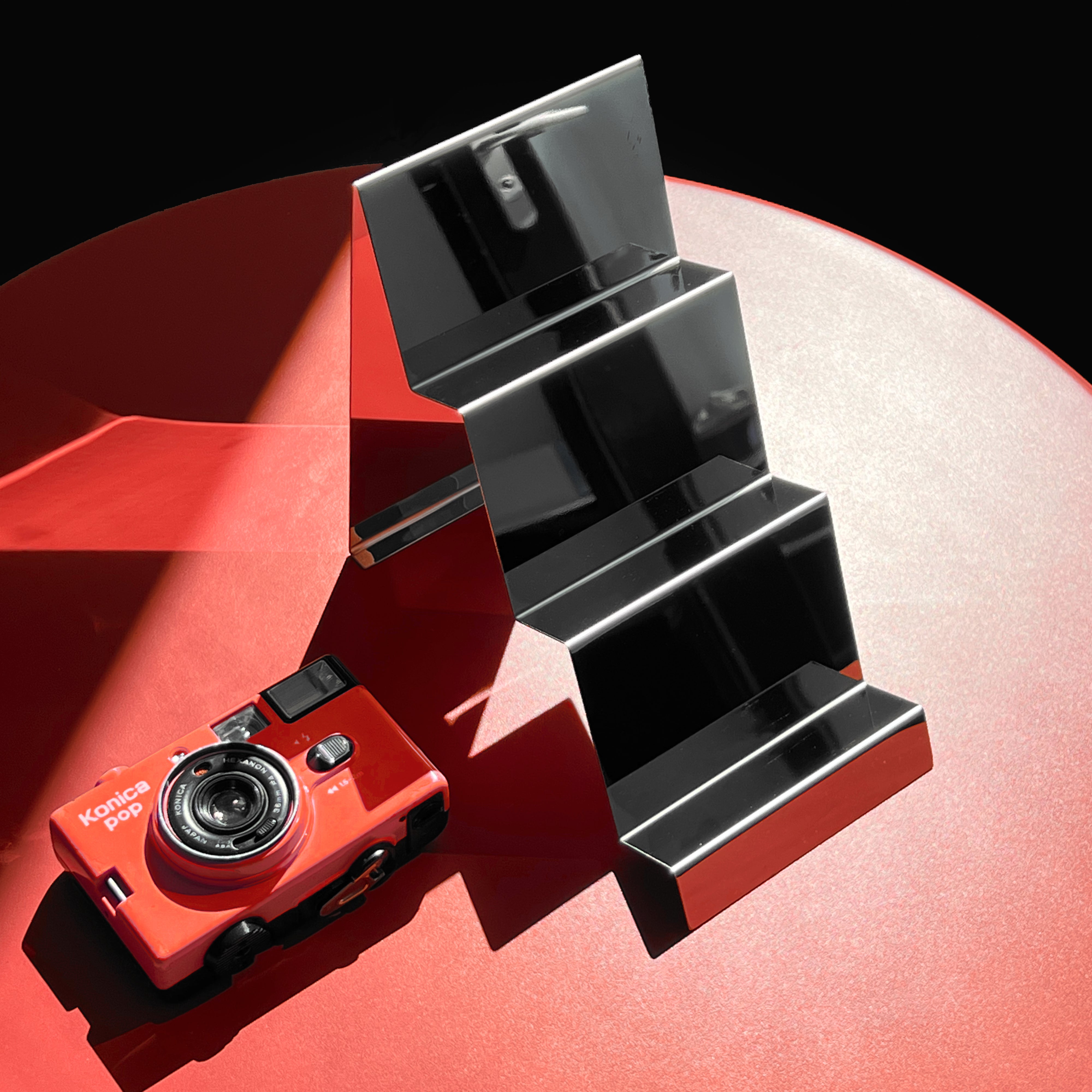 Premium reflective camera display stand from the side, highlighting its two-step design.