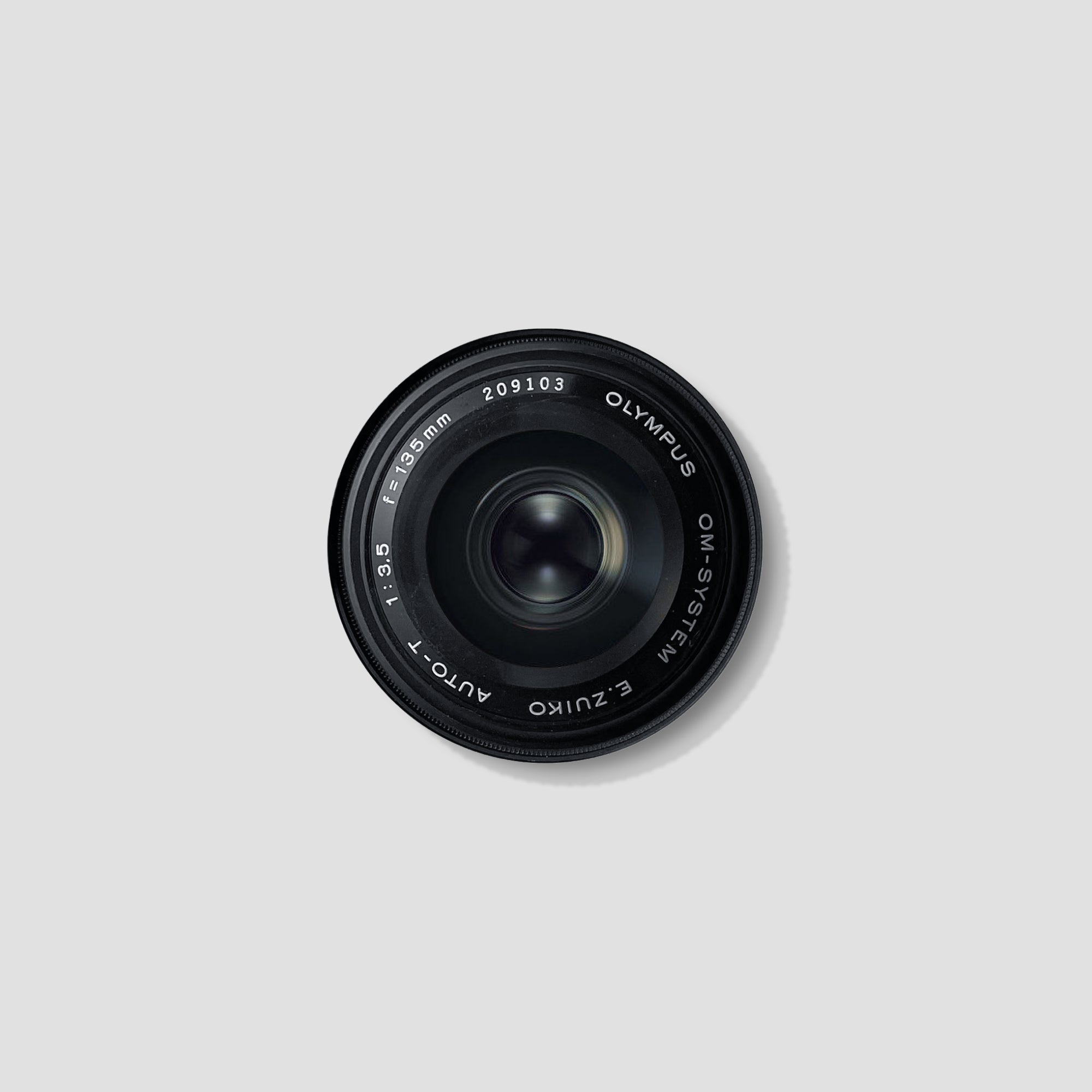 Close-up of Olympus OM-System 135mm f/3.5 lens highlighting its compact design and optical quality.