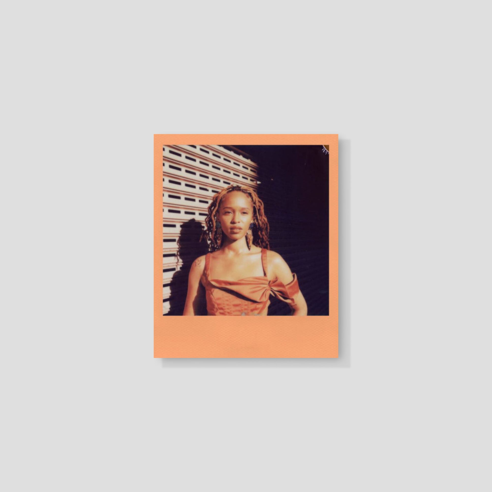 Polaroid camera using Peach Fuzz film outdoors, capturing a sunny day.