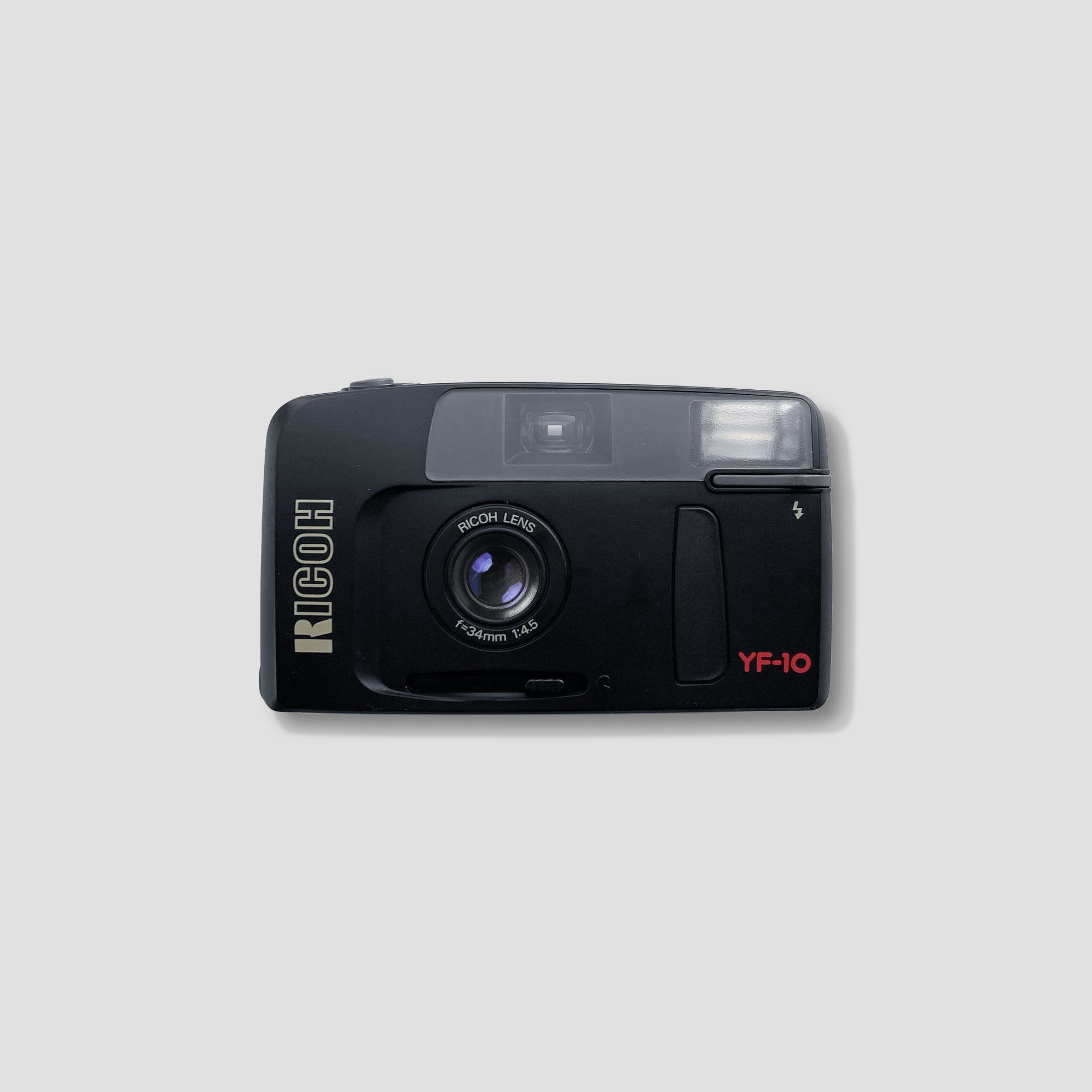 Front view of Ricoh YF-10 compact 35mm film camera on a travel table