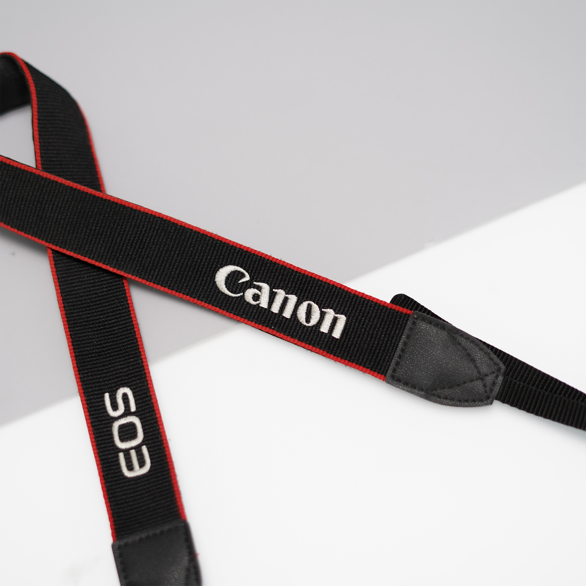 Close-up of black Canon strap with embroidered logo on DSLR camera