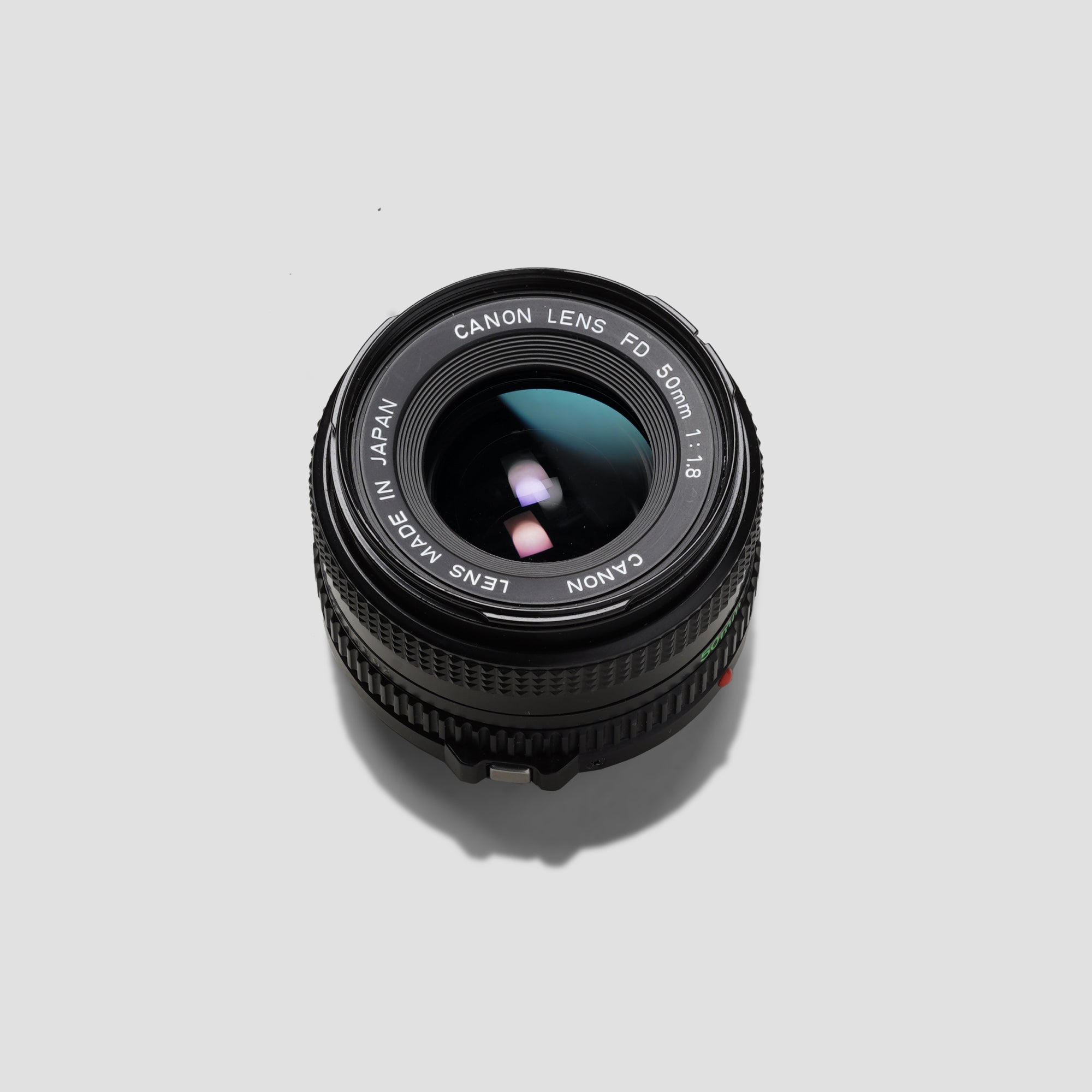 Close-up of Canon FD 50mm 1.8 lens showing its compact design and sharpness.