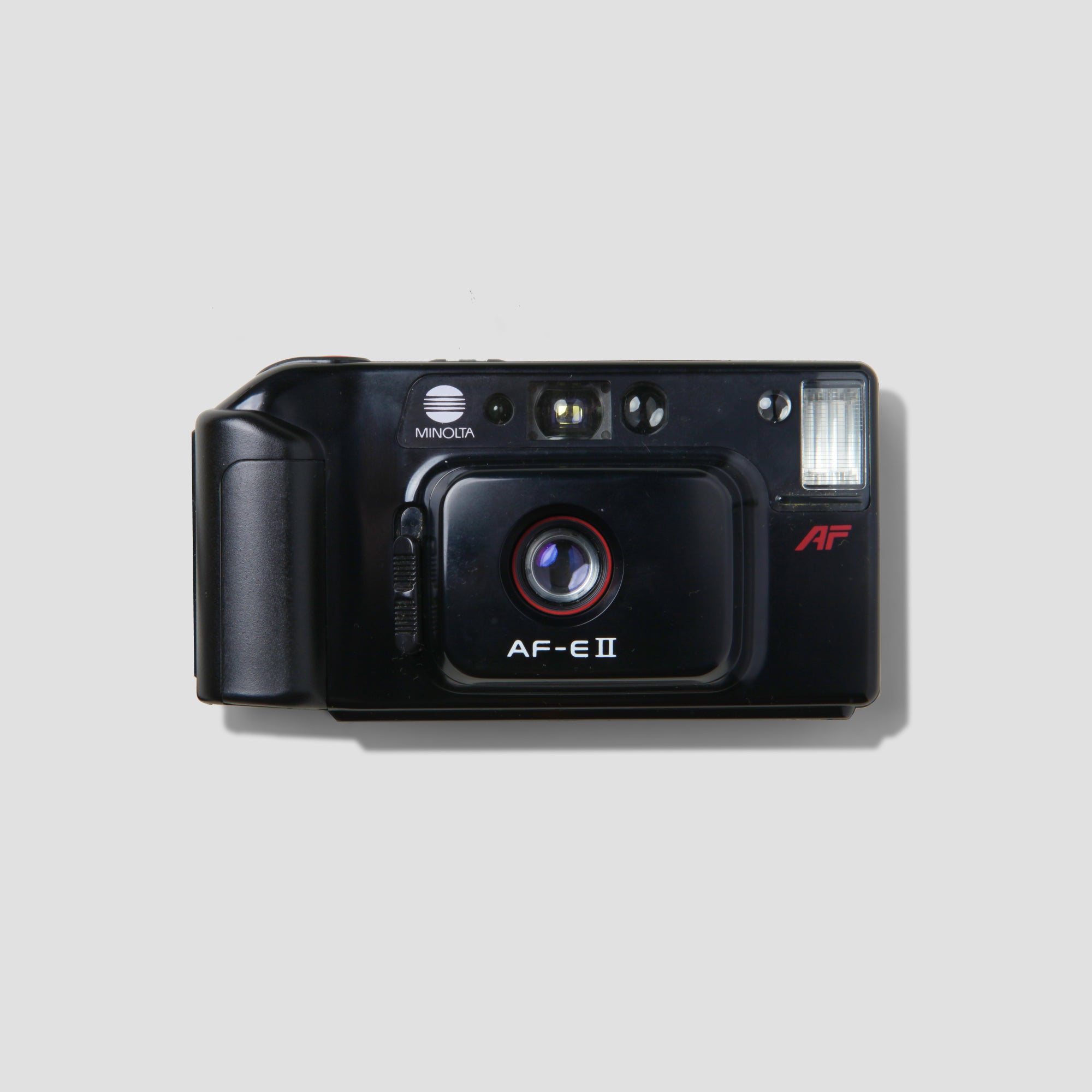 Close-up of the Minolta AF-E II film camera with autofocus feature in action.