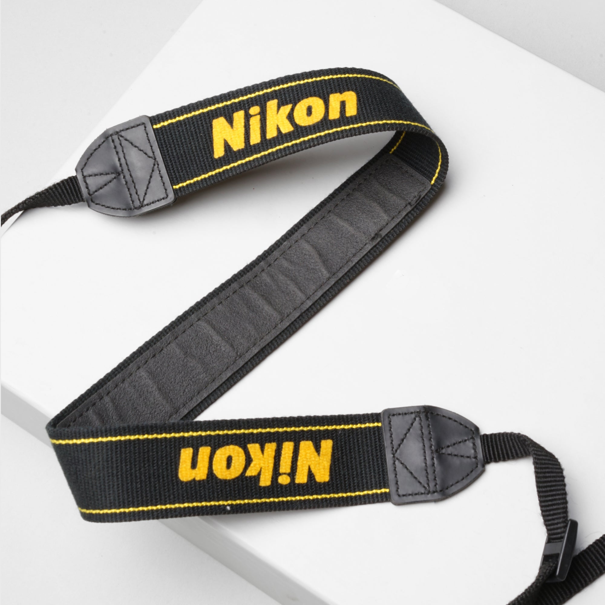 Nikon original strap attached to DSLR camera, showing embroidered logo