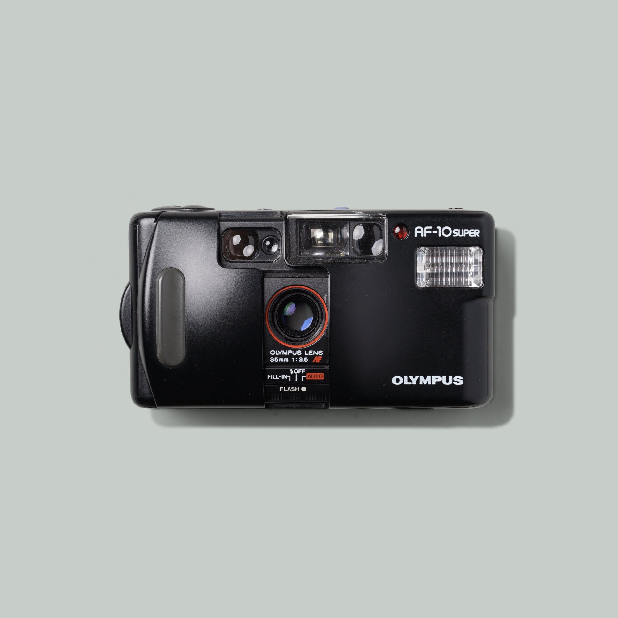 Close-up of Olympus AF-10 Super lens and controls, demonstrating its compact design
