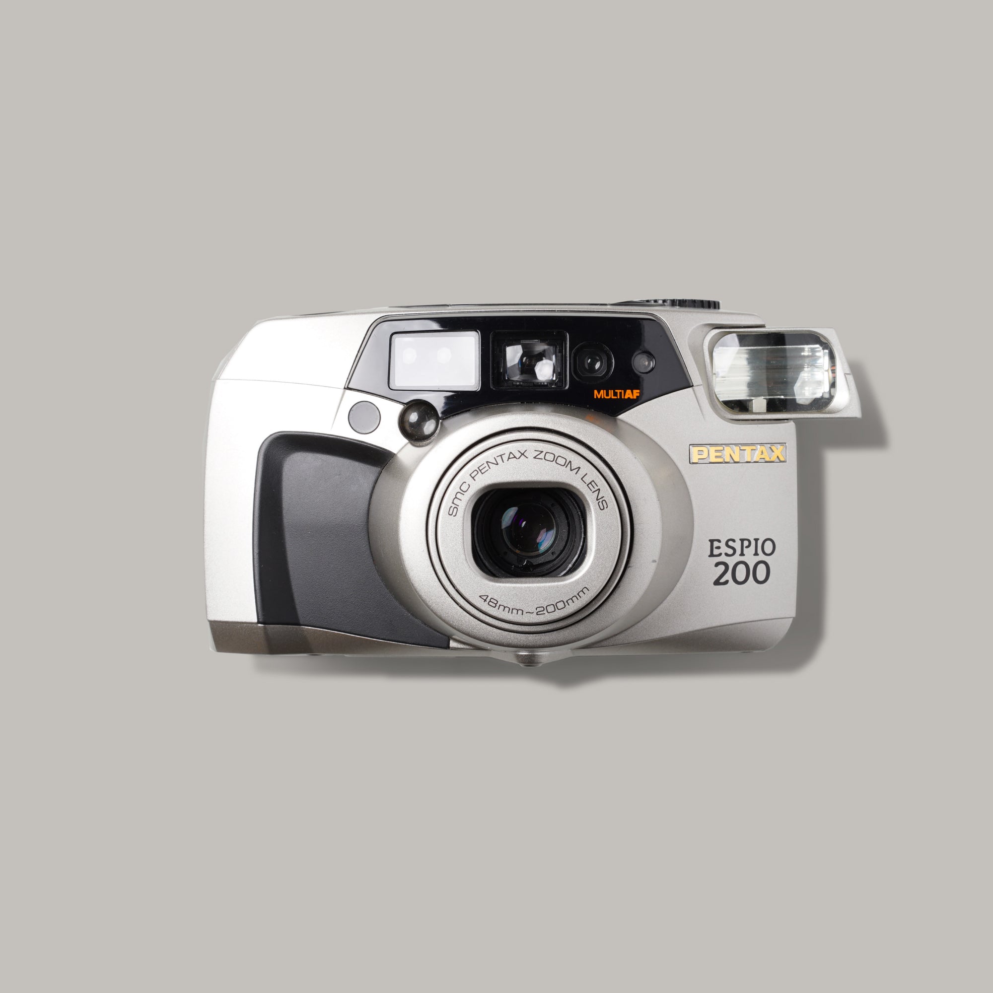 Close-up of the Pentax Espio 200 compact film camera showing its sleek grey design and zoom lens.